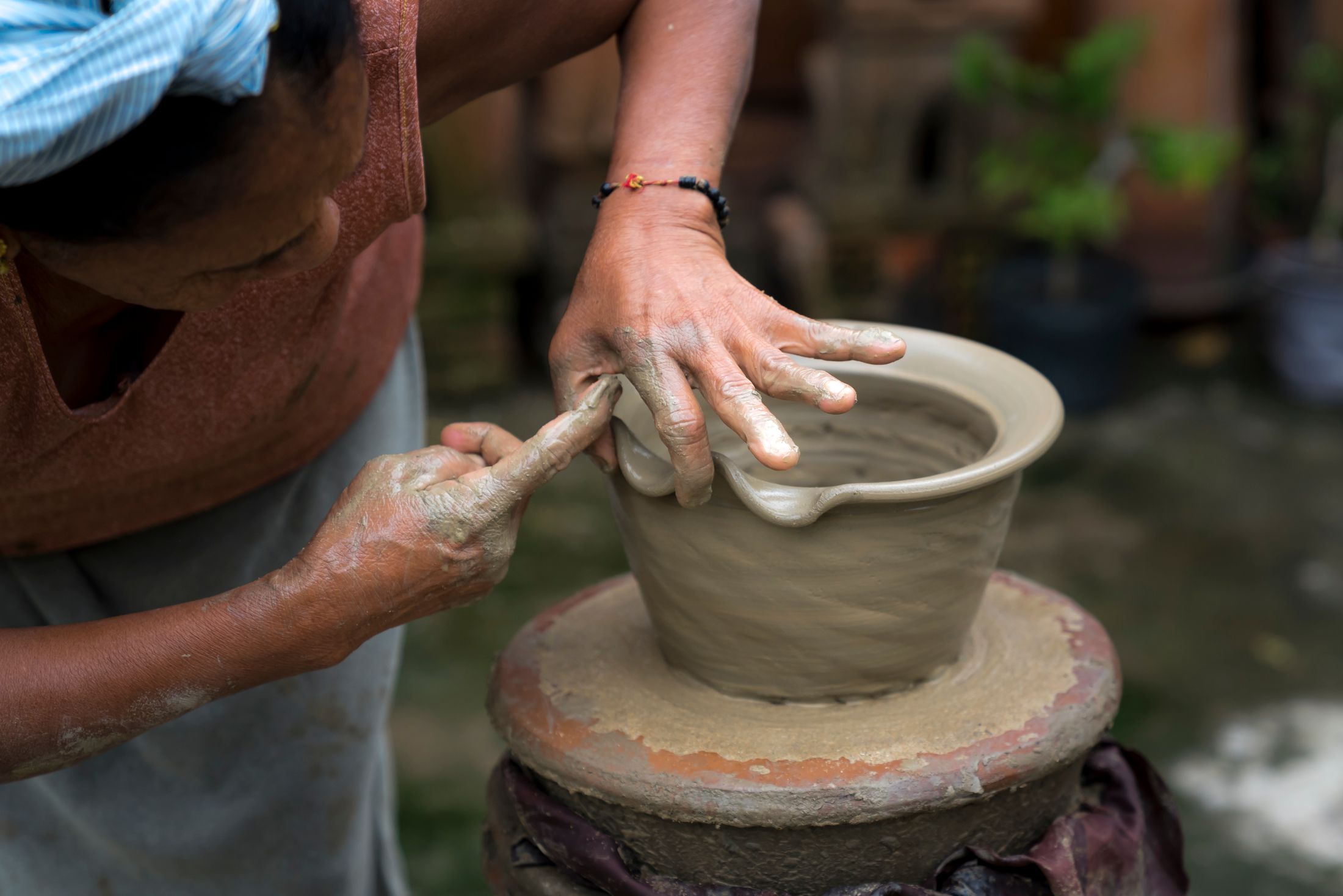A potter's hands shaping clay on a wheel